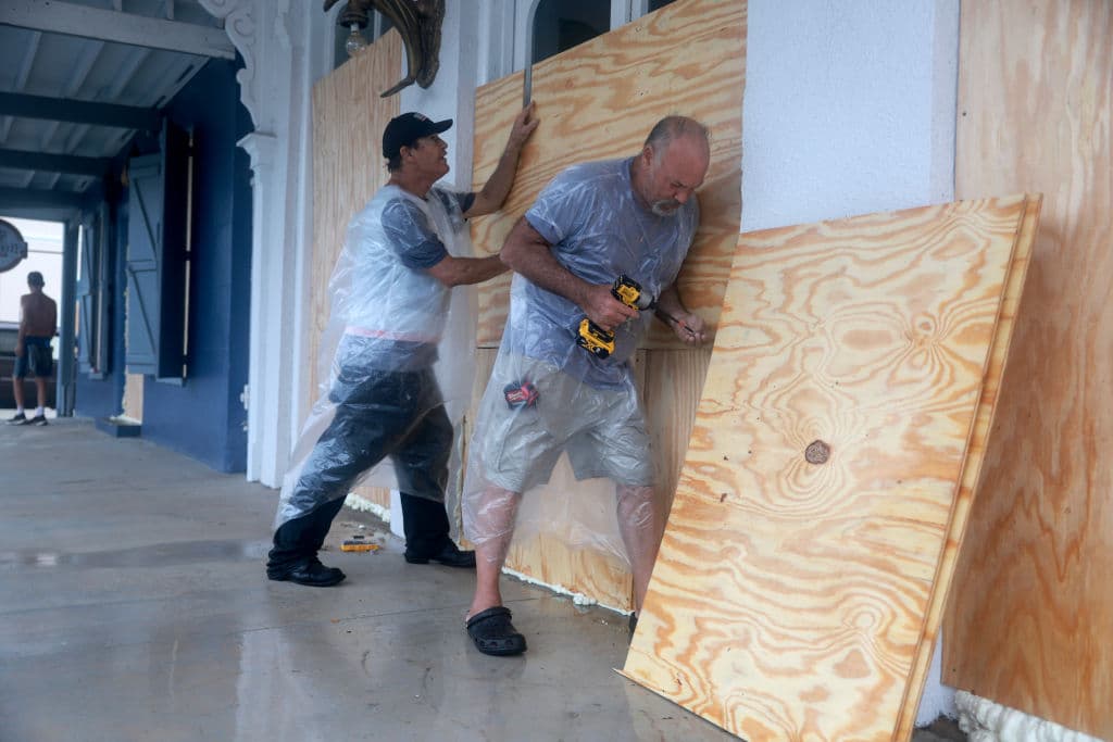 Tom Street (I) y Dan Norman colocan contrachapado sobre las ventanas de un negocio mientras se preparan para la posible llegada de la tormenta tropical Debby, que se fortalece a medida que avanza por el Golfo de México el 04 de agosto de 2024 en Cedar Key, Florida.