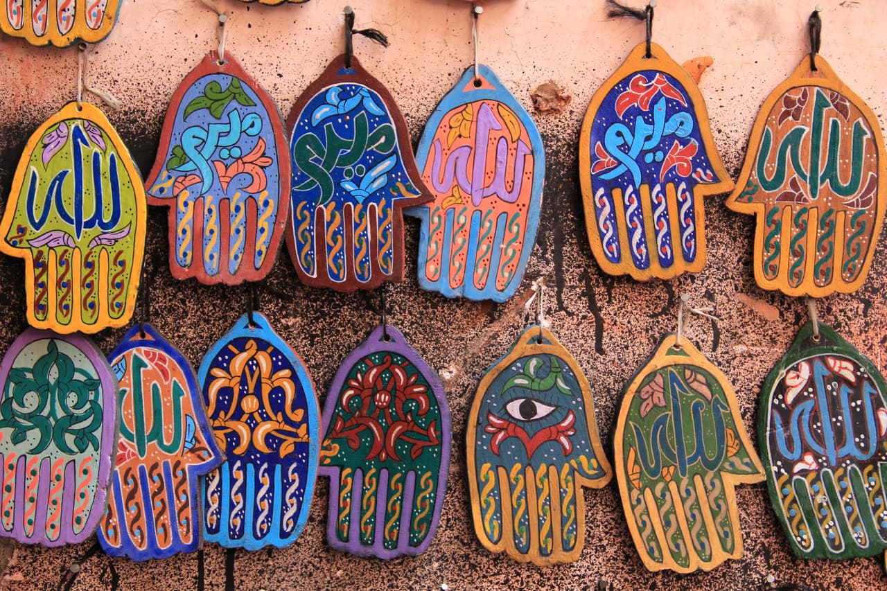 <b>Mano de Fátima o Jamsa</b>
<br>Este símbolo es típico en las culturas musulmanas y judías sefardíes, donde posee el mismo significado: "cinco". El amuleto, también conocido como "la mano de Dios", proviene desde la antigüedad y se puede apreciar en la iconografía judía ya a partir del año 244 D.C. en los frescos de la Sinagoga de Dura Europos. Según los especialistas, la mano protege del mal al detenerlo con la palma de la mano, previene las enfermedades y atrae la buena suerte.