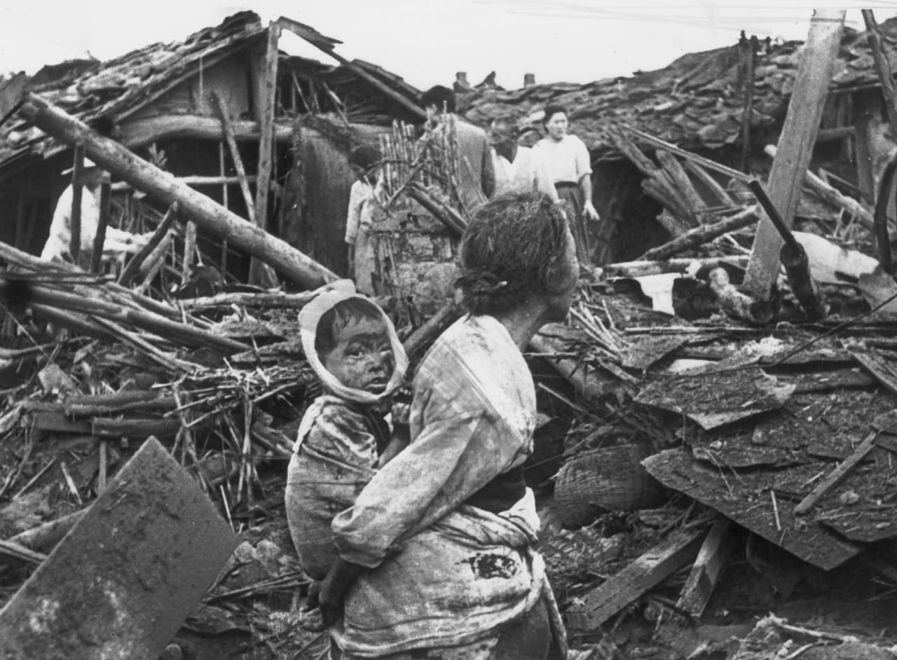 Una mujer y su nieto caminan sobre las ruinas de su casa, destruida tras un bombardeo de Estados Unidos sobre Pyongyang durante la guerra de Corea.