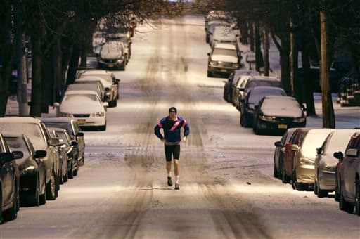 Un corredor toma su camino a lo largo de una calle cubierta de nieve en el barrio de Hudson Park en Albany, Nueva York.