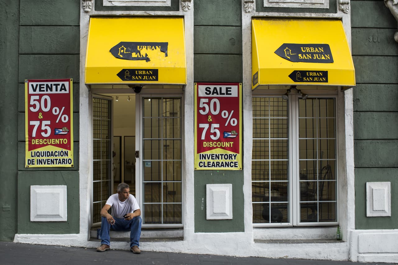Un hombre permanece sentado frente a una tienda en liquidación en el Viejo San Juan. 29 de abril de 2016.