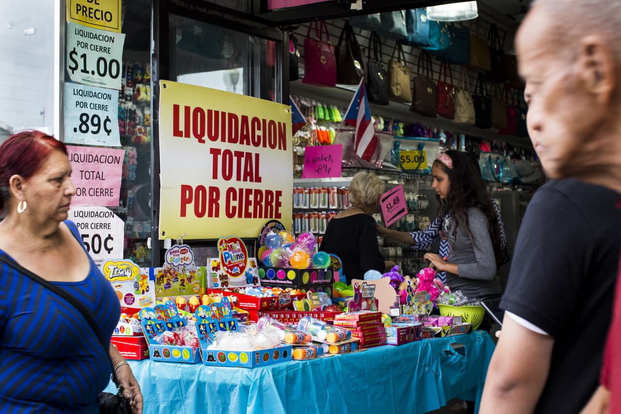 CIudadanos caminan frente a una tienda que está en liquidación en la zona de Río Piedras, en San Juan. 30 de abril de 2016