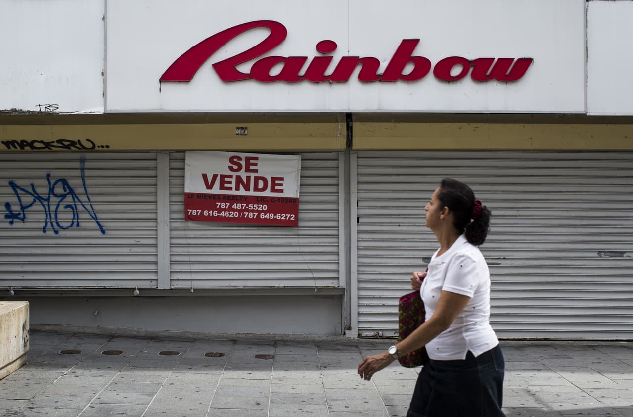 Un peatón pasa frente a una tienda cerrada que está en venta en Río Piedras, vecindario de San Juan, Puerto Rico. 30 de abril de 2016.
