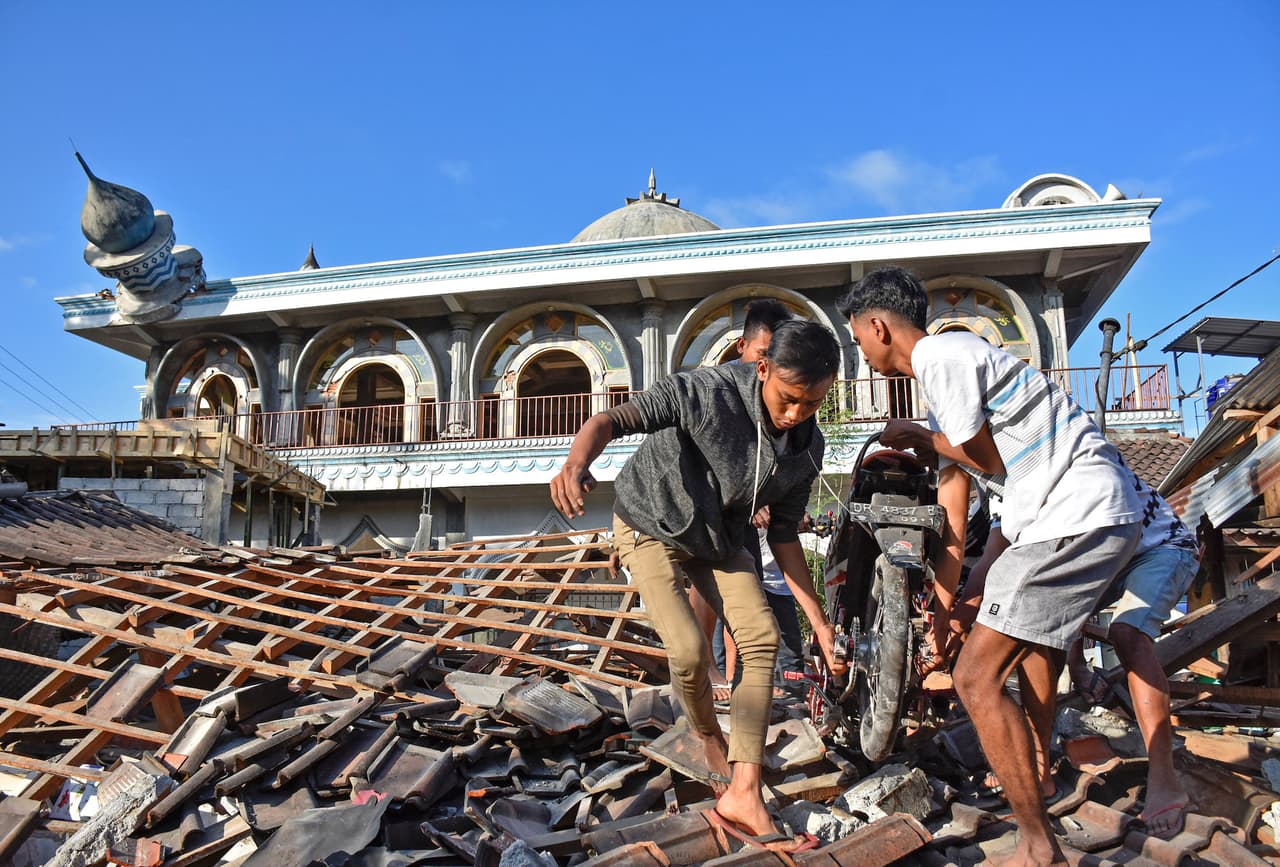 Jóvenes recuperan una motocicleta de una casa seriamente dañada cerca de una mezquita. En algunos lugares de Lombok las tuberías de agua salen del suelo, agrietadas y goteando por la fuerza del terremoto.