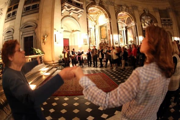 Miles de personas con impermeables por la lluvia, mochilas, bolsos, sombreros y banderas, circulan entre las iglesias.