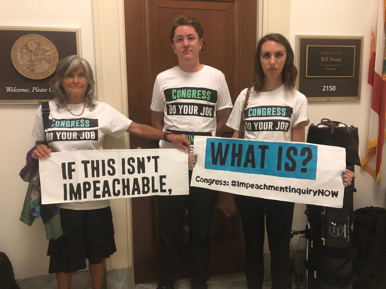 Molly Pauker, Ian Madrigal y Sophie Lassoff llegaron a la audiencia con carteles en los que se podía leer: 'Si esto no es digno de impeachment, ¿qué es?'