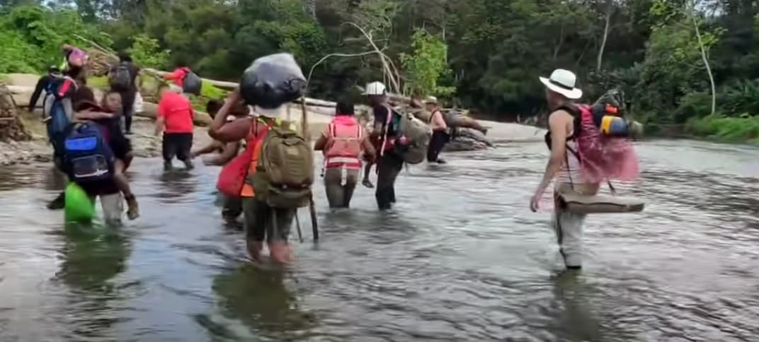 Un grupo de inmigrantes cruzan un río dentro de la selva de Darién.