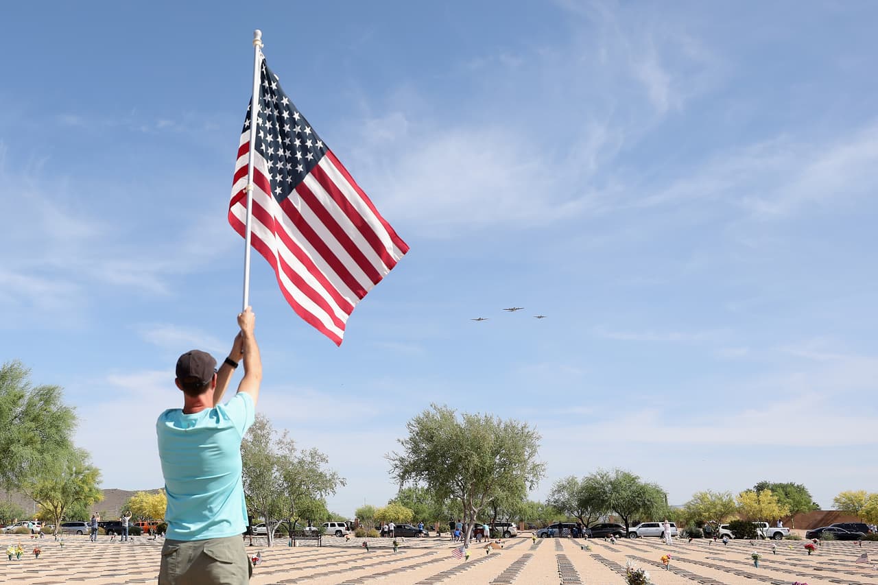 Steve Judge, ondea una bandera estadounidense cuando un bombardero B-17 "Flying Fortress", un B-25 Mitchell y un C-47 Skytrain sobrevuelan el área de Phoenix en honor al 75 aniversario de la victoria en Europa y al final de la Segunda Guerra Mundial.