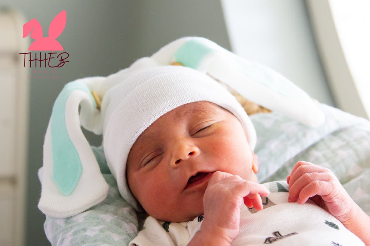 Este bebé recién nacido posa con unas enormes orejas de conejo de pascua.