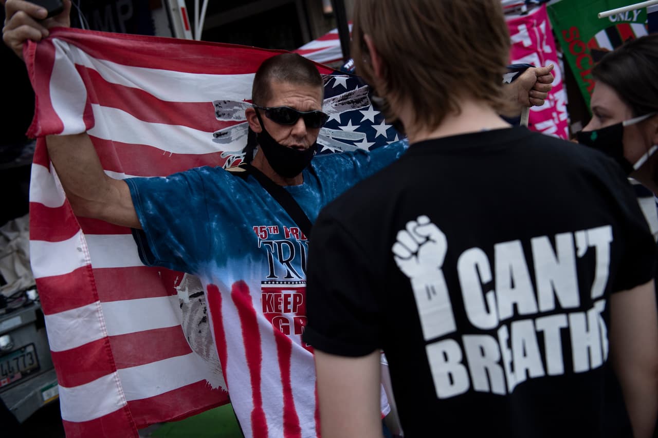 Un simpatizante de Trump y un manifestante hablan en las afueras de la instalación del evento masivo, el primero que realiza el mandatario desde mediados de marzo, cuando arreció la pandemia y fueron cancelados todos los eventos con aglomeraciones de personas.