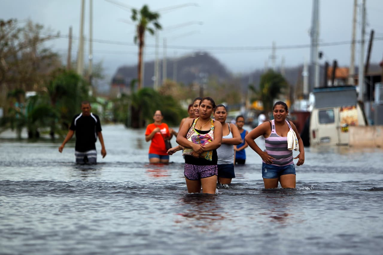 Residentes de San Juan caminan por las aguas de las calles inundadas. El gobernador de la isla advirtió del daño estructural en la represa de Guajataca, por lo que se realiza una evacuación masiva de las poblaciones en peligro.