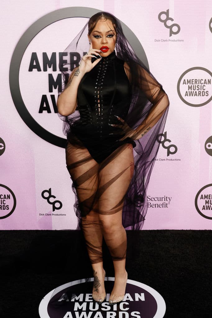 Latto, intérprete de ‘For the night’, causó revuelo con un corsé de cuello halter color negro, el cual cubrió con un manto de tul, y zapatillas transparentes de Femme LA.