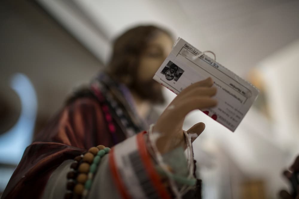 Una figura de Jesucristo sostiene documentos de inmigración que han sido dejados por deportados que pasan por la Casa del Migrante en Ciudad Juárez.