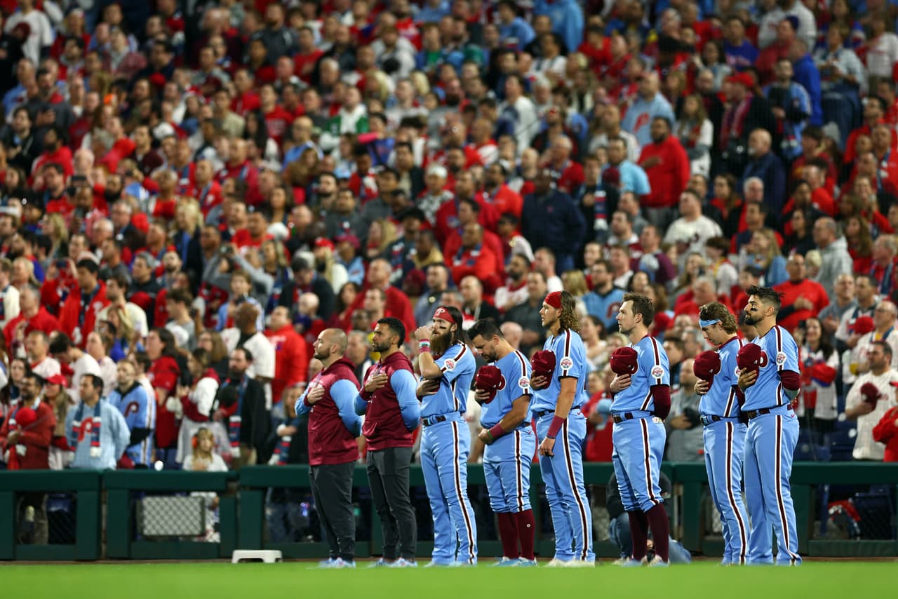 Los jugadores de los Filis de Filadelfia miran durante el himno nacional antes de jugar contra los Astros de Houston en el Juego Cinco de la Serie Mundial 2022