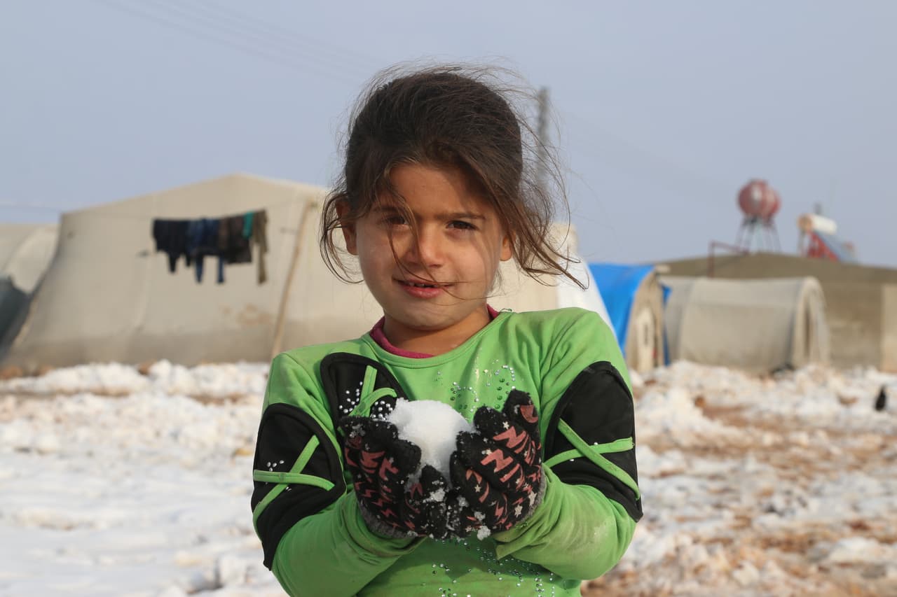 Una pequeña juega con una bola de nieve con sus amigos, en el campamento de desplazados de Al-Nour, Siria. "Desearía tener mi abrigo amarillo que amo. Lo usaba cuando nevaba y nunca sentía frío", dijo.