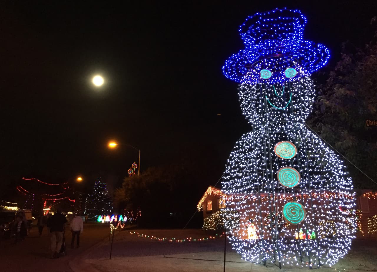 Un muñeco de luces gigante decora la esquina de una calle que junto a la luna iluminan el festival.