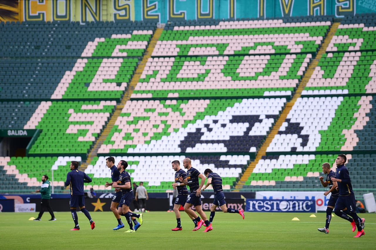 Jugadores de Pumas calientan con la tribuna completamente vacía.