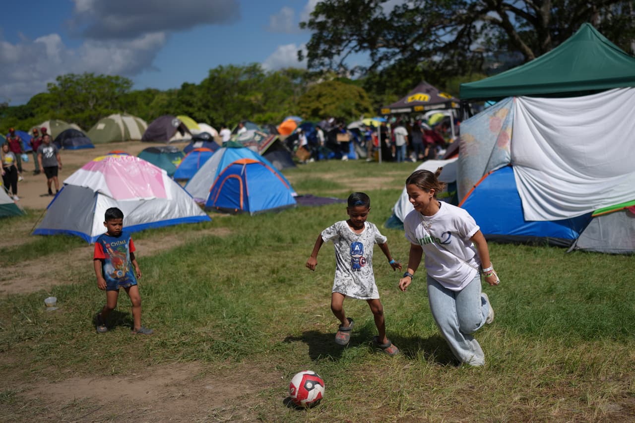 Una voluntaria juega al fútbol con niños en el Parque Francisco de Miranda, donde se encuentran acampando personas cuyas casas resultaron dañadas por los recientes terremotos, el miércoles 1 de julio de 2026, en Caracas, Venezuela. (AP Foto/Matías Delacroix)
