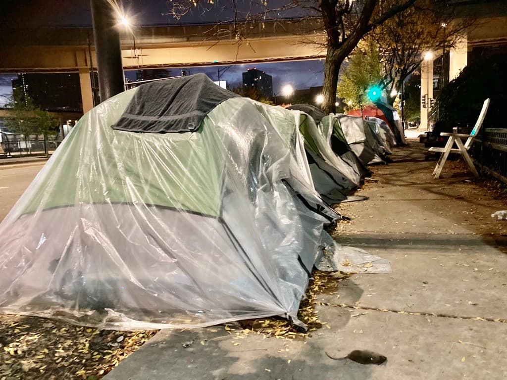 Migrantes ponen plástico sobre las carpas para evitar que la lluvia y el frío los soprenda.
