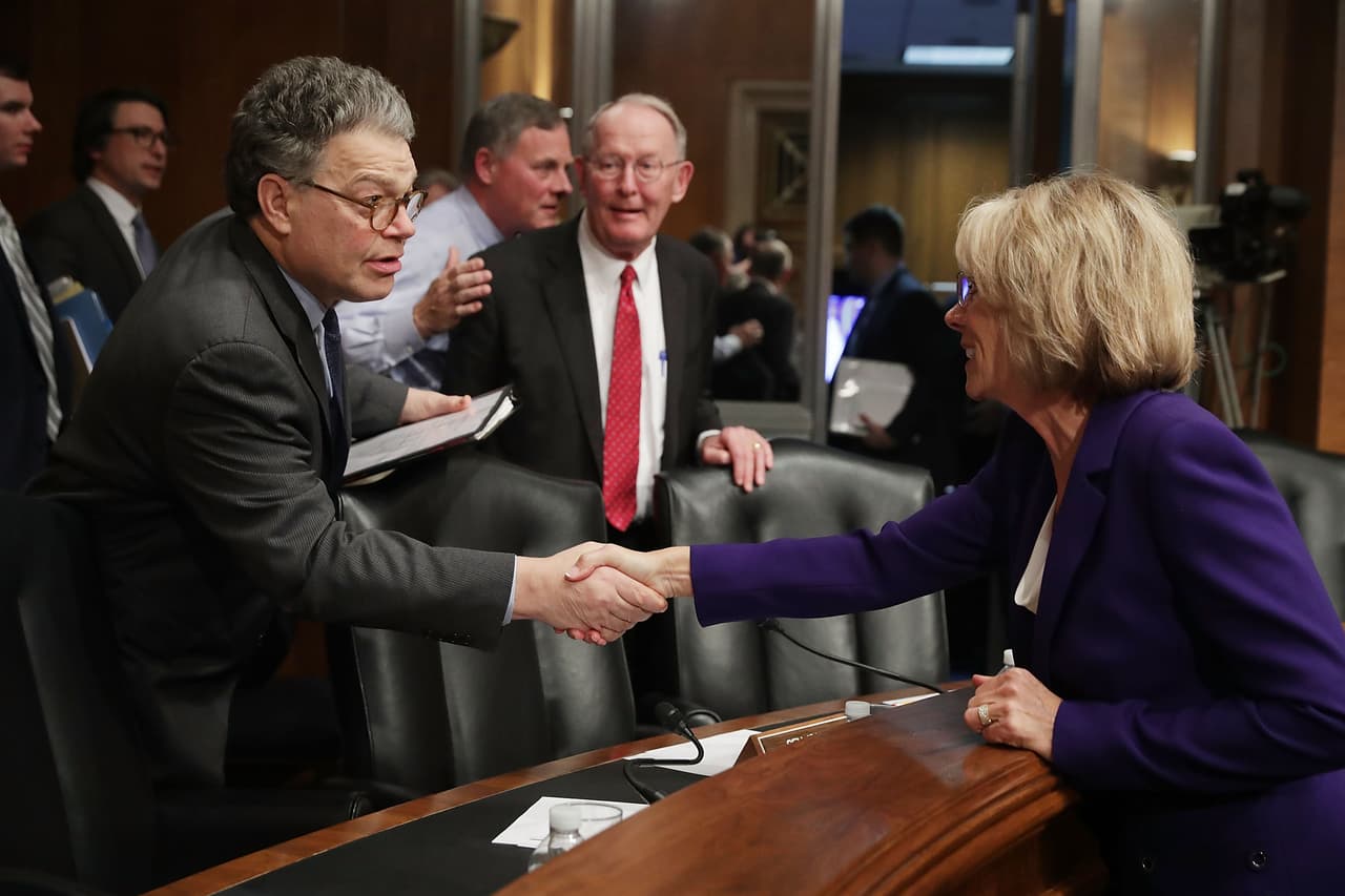 DeVos le dijo al senador Al Franken (izquierda) que preferiría un sistema que les asigne los fondos a los estudiantes, no a las escuelas.