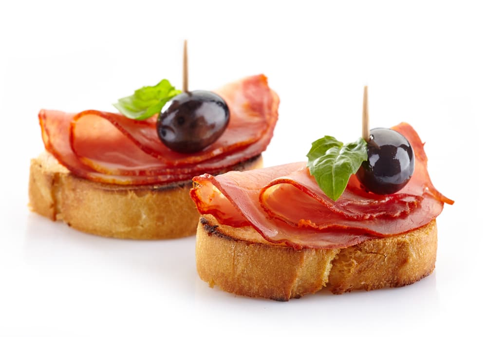 Jamón artesanal y aceituna. Puedes experimentar con unos bocadillos al estilo de tapas españolas, solo incorpora el jamón artesanal y dale un sabor fresco pero consiste con las aceitunas. A tus invitados les encantarán.