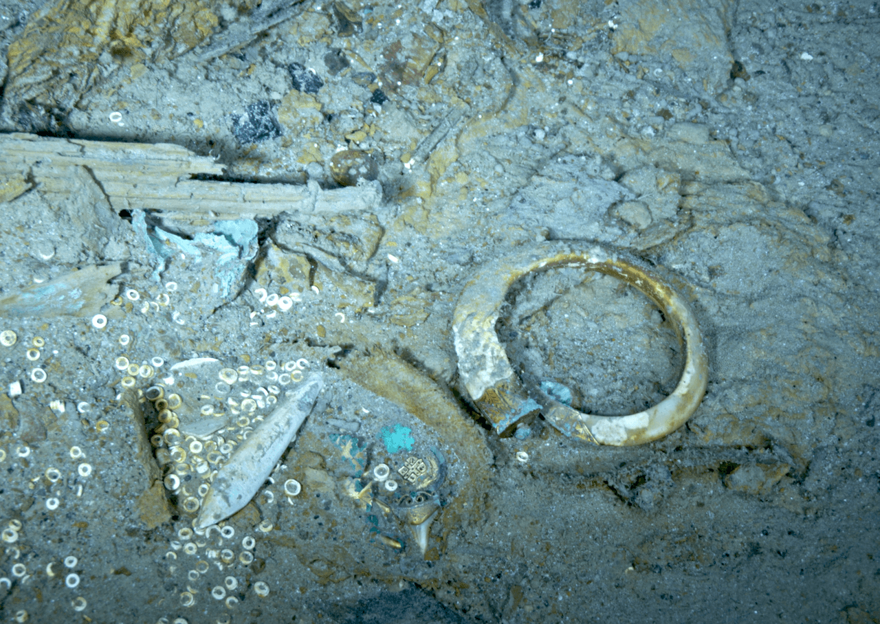 Un colgante con forma de diente de tiburón, un reloj de bolsillo y un brazalete con forma de colmillo de jabalí en el campo de escombros del escaneo del gemelo digital del Titanic.