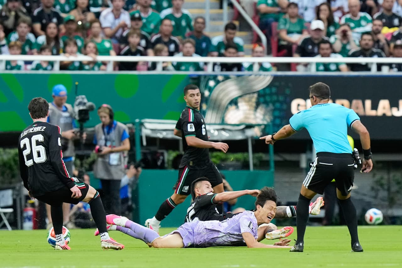 El árbitro uruguayo Gustavo Tejera hace un gesto mientras el mexicano Roberto Alvarado (25) disputa el balón con el surcoreano Lee Jae-sung (abajo) durante el partido de fútbol del Grupo A de la Copa del Mundo entre México y Corea del Sur, en Zapopan, cerca de Guadalajara.
