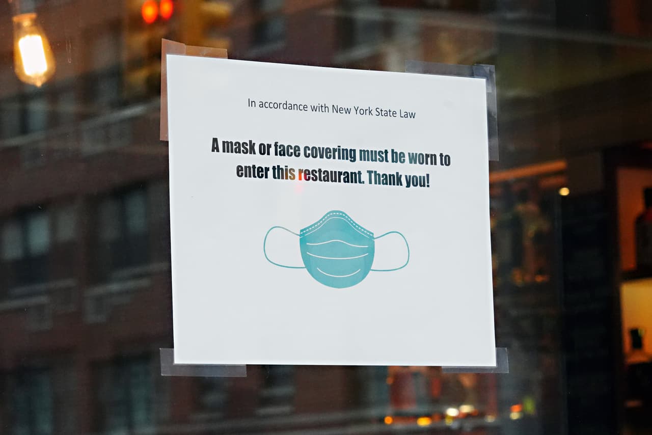 Un letrero en la ventana de un restaurante en Nueva York dice: "Se debe usar una máscara o un cubre-cara en todo el restaurante. ¡Gracias! " Este mes, el gobernador Andrew Cuomo declaró que los neoyorquinos deben por ley taparse la cara en espacios públicos donde se no se puedan observar las normas de distancia social.