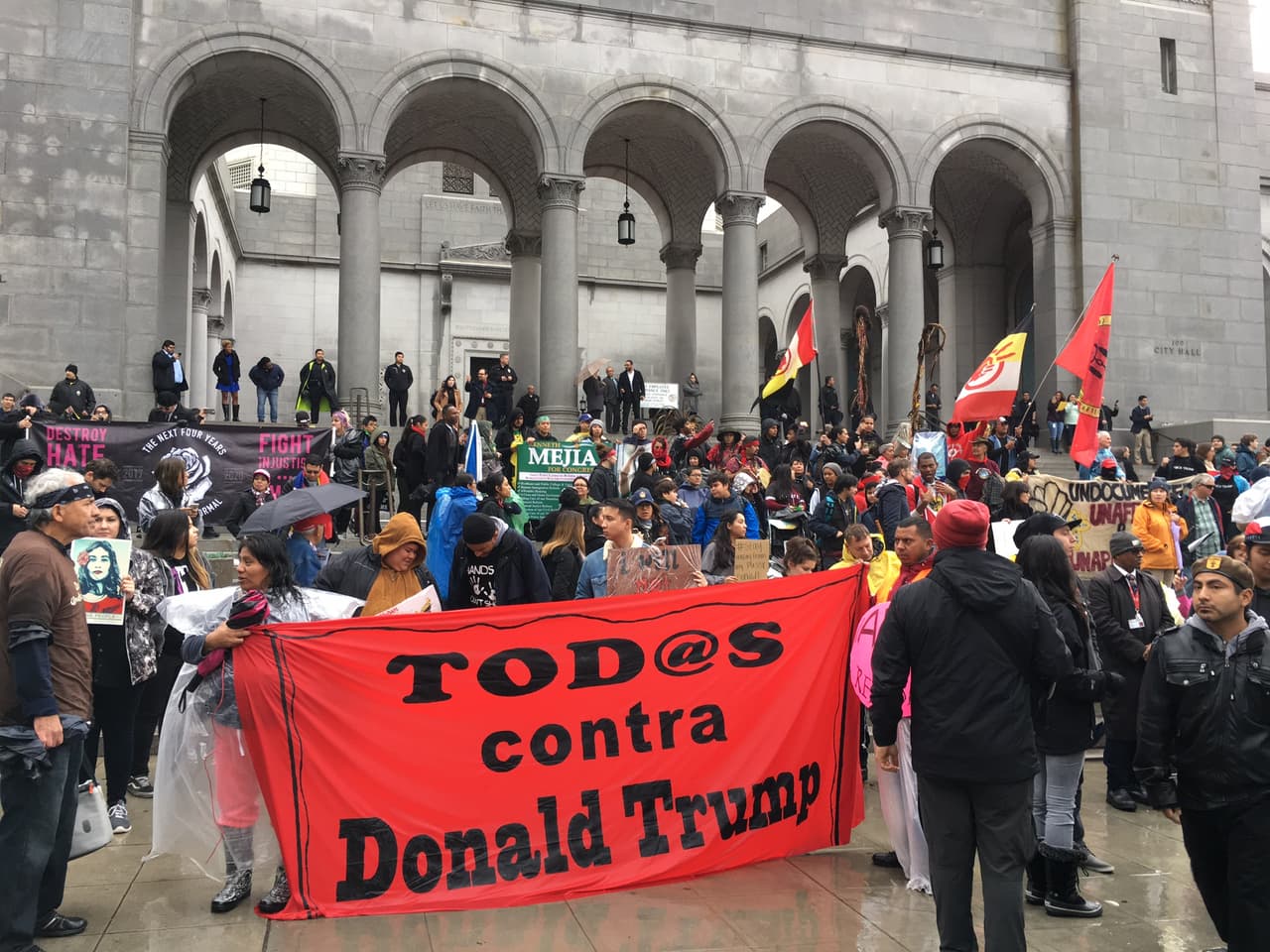Inmigrantes sosteniendo una manta con la frase: “Todos contra Donald Trump”.