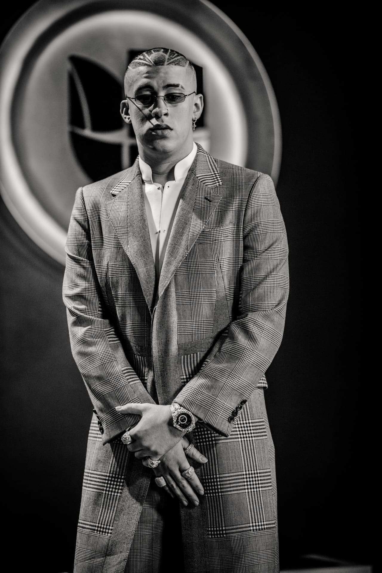 La pose de manos entrelazadas no es ajena a Bad Bunny. Aquí mira fijamente a las cámaras, serio y consciente de su creciente relevancia en la escena musical. En los últimos doce meses el nombre de Bad Bunny ha pasado de tener escasa relevancia Google a estar disparado en interés en el buscador (
<a href="https://trends.google.com/trends/explore?date=2016-02-01%202018-02-23&q=bad%20bunny">según Google Trends</a>).