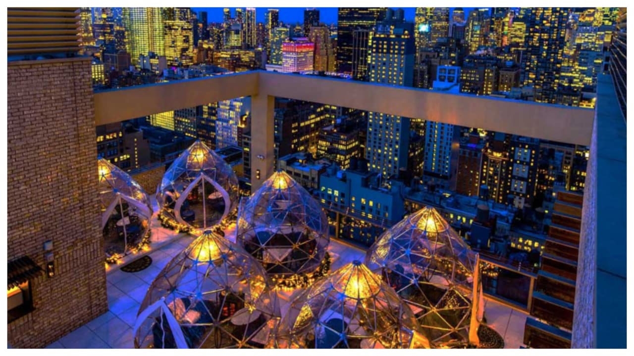 Ubicados en 
<a href="https://www.google.com/maps/dir/Somewhere+Nowhere+NYC+-+Lounge,+Nightclub+%26+Rooftop+Pool,+112+W+25th+St,+New+York,+NY+10001/''/@40.7442991,-74.0627356,12z/data=!3m2!4b1!5s0x89c259a51c5923d9:0x14e6167382a31db2!4m13!4m12!1m5!1m1!1s0x89c259cb2d7e8c45:0x2d3518f1f16b50!2m2!1d-73.9926957!2d40.7443203!1m5!1m1!1s0x89c259cb2d7e8c45:0x2d3518f1f16b50!2m2!1d-73.9926957!2d40.7443203">112 West 25th Street</a>, estos iglús cuentan con calefacción y están completamente amueblados con un lujoso sofá de dos plazas, sillas de terciopelo, una chimenea empotrada y mantas de piel donde los invitados y sus amigos pueden disfrutar de cócteles, pequeños bocados y 
<b>vistas despejadas del horizonte de NYC</b>. Para reservar debes llamar al: Tel. (212) 404-7969.