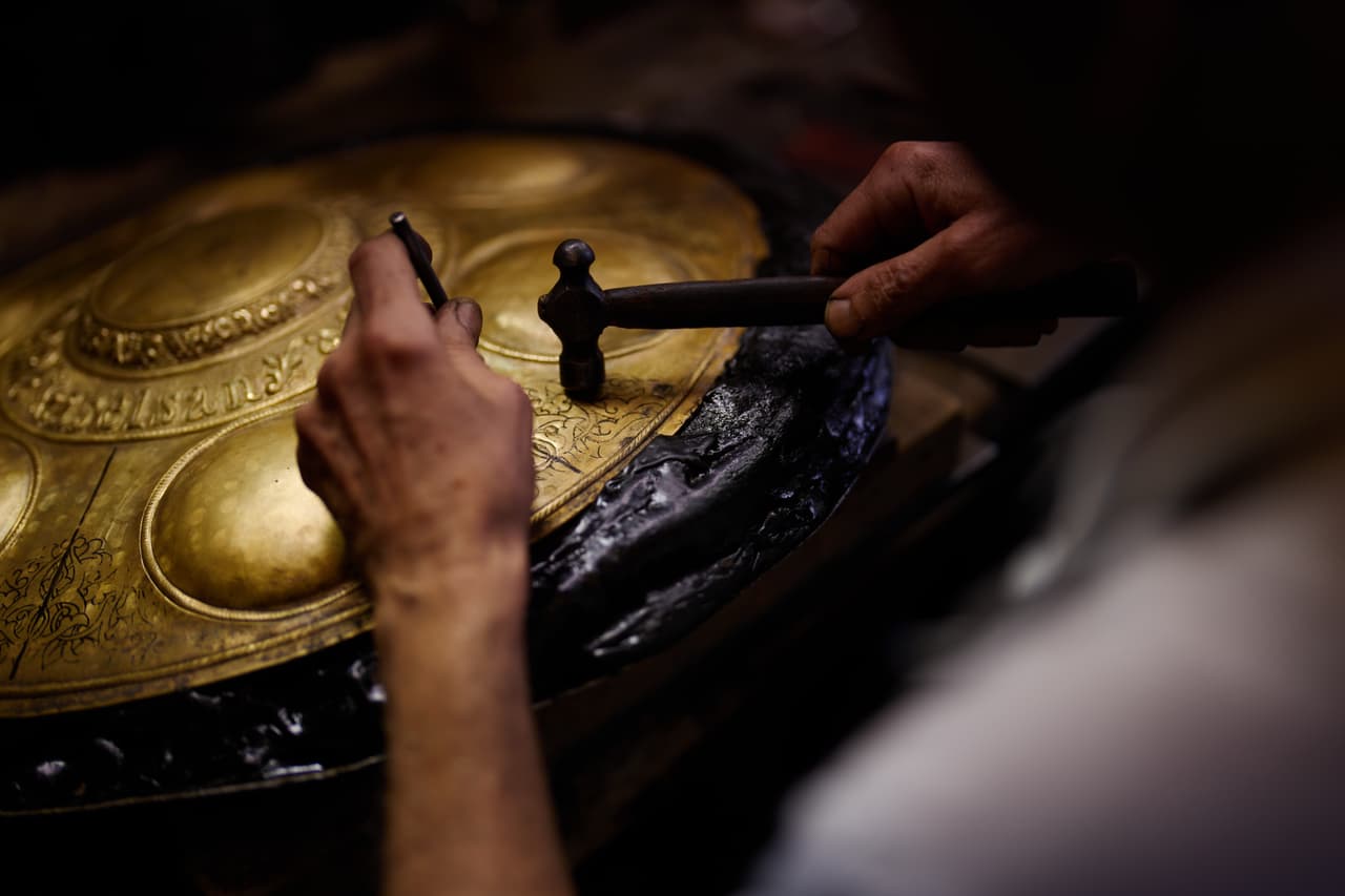 El maestro artesano de incrustaciones y relieves, Halit Cakar, trabaja en una pieza de metal en su taller en el distrito comercial de Eminönü, en Estambul.