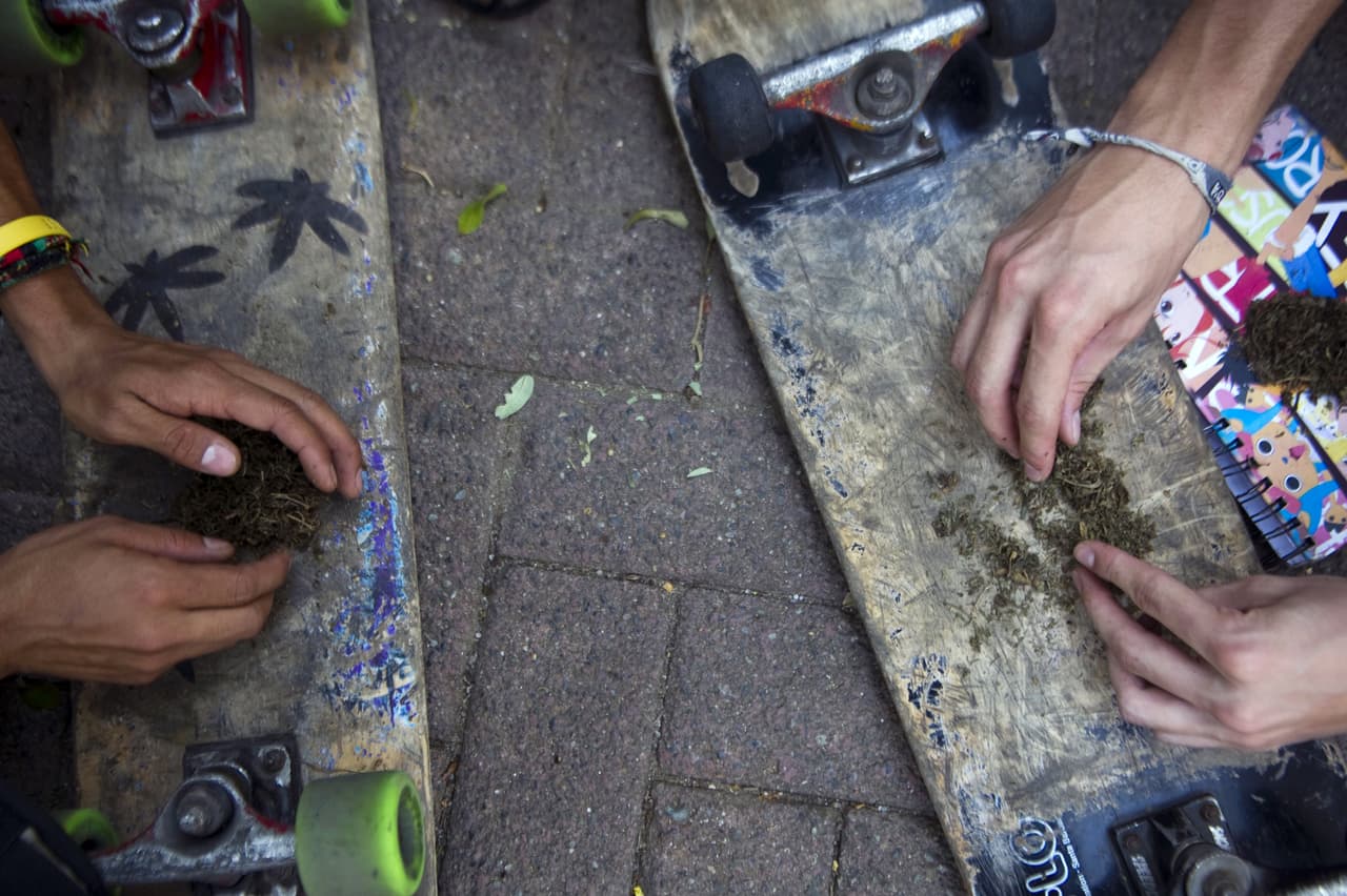 Dos jóvenes se hacen un cigarro de marihuana en Medellín.