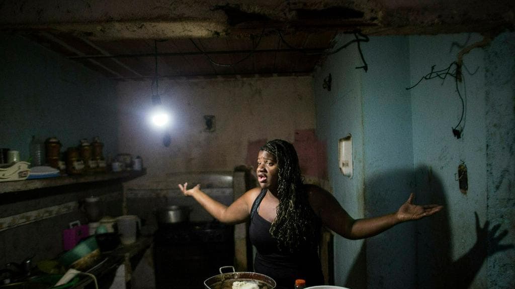 Dugleidi Salcedo complains to a neighbor about the high price of food while preparing arepas for her three children in the kitchen of her home in the Petare neighborhood of Caracas, February 14, 2019.