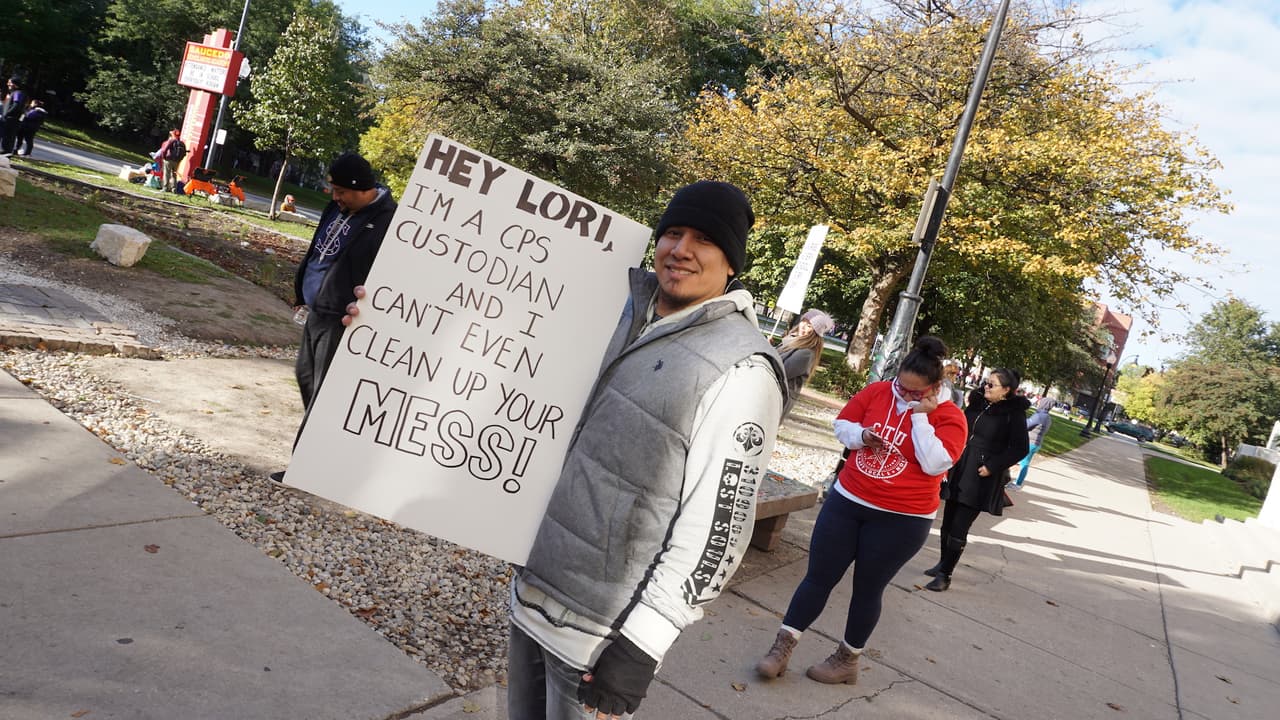Jesse Torres, porta una pancarta donde se lee "Hey Lori, soy un custodio de CPS y no puedo limpiar tu desastre".