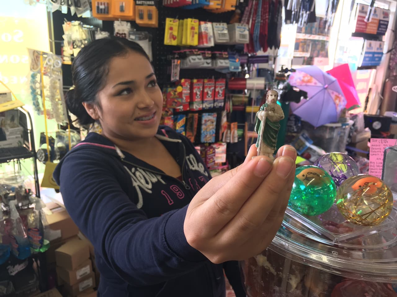 Maritza Barbosa, responsable de una tienda en Sur Los Ángeles, muestra una pequeña figura de San Judas Tadeo, considerado uno de los santos más milagrosos.