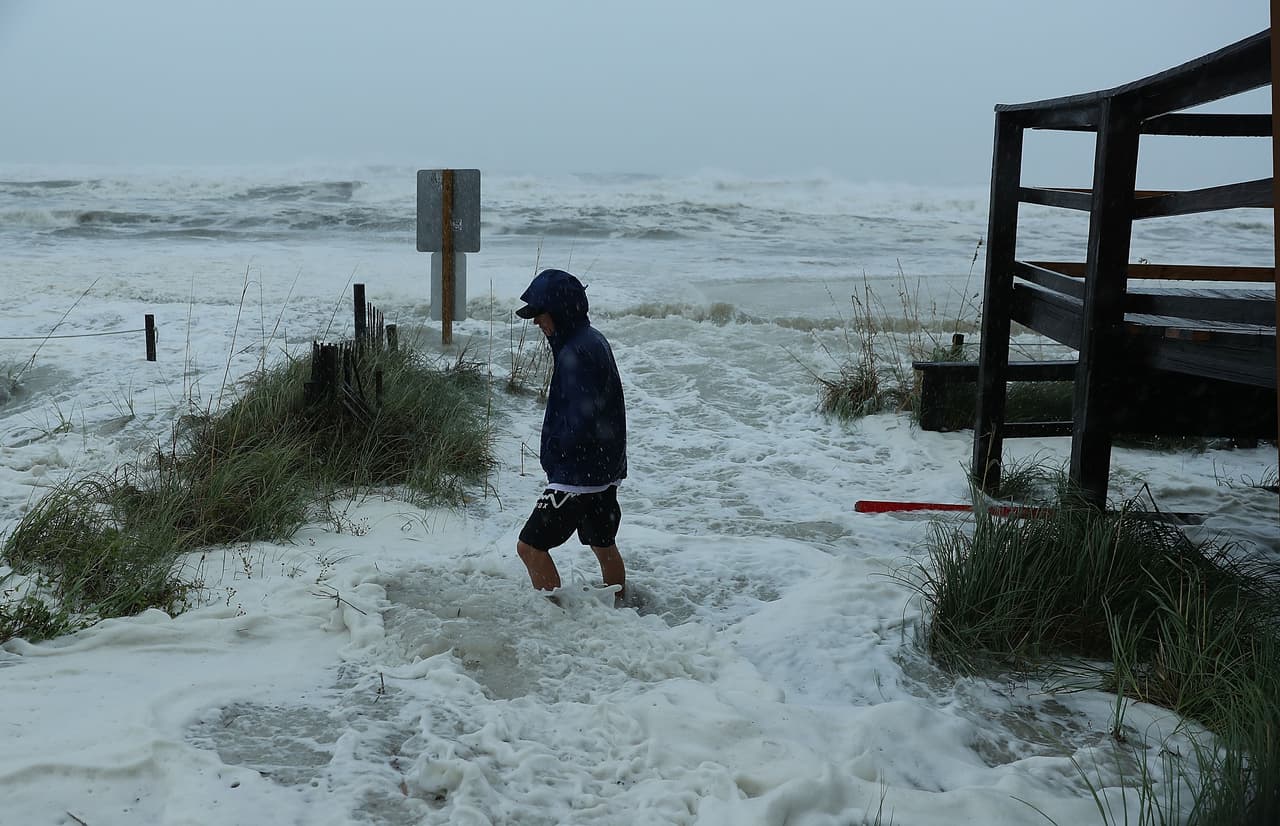 Un residente de Panama City camina por las aguas que comienzan a ser impulsadas por la marea ciclónica sobre la playa. El pronóstico indica que tocará tierra cerca de este lugar después del mediodía del miércoles.