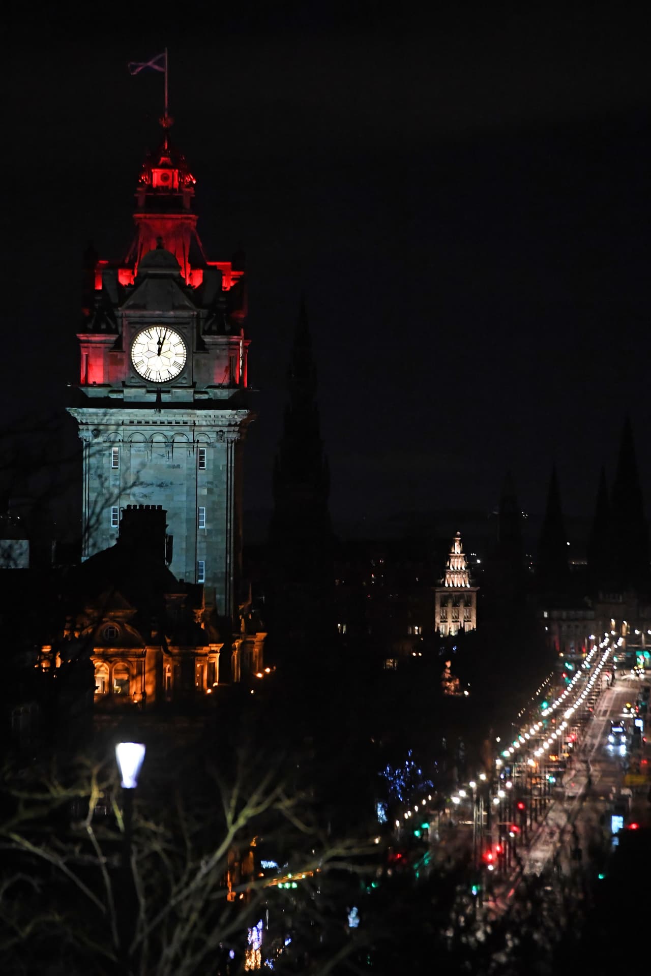 Una Princes Street casi desierta en Edimburgo es mostrada en la imagen a medida que pasa la medianoche, que se muestra en el reloj del Hotel Balmoral.
