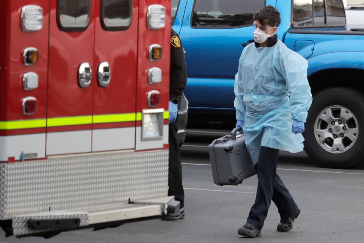 Un trabajador de la ambulancia de bomberos y rescate de Kirkland camina cerca de una segunda ambulancia después de que un paciente fuera llevadp en ambulancia por un posible brote de coronavirus en ele stado de Washington.