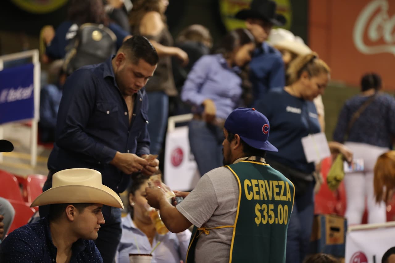 Un fanático compra su cerveza a uno de los vendedores del palenque.