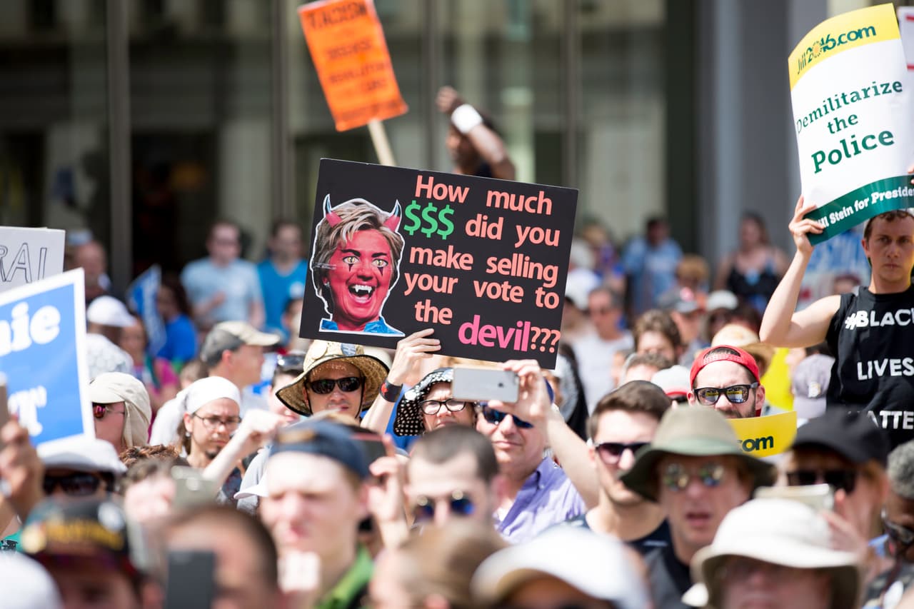 MARTES 26 DE JULIO. 1:59 PM. Muchos no están de acuerdo con Sanders en apoyar a Hillary Clinton en las elecciones de noviembre. Por eso encuentran en el partido verde la continuación de las ideas ofrecidas por el senador demócrata durante su campaña. En la foto, el cartel de la manifestante tiene escrito “¿Cuánto dinero ganaste vendiendo tu voto al diablo”, en clara alusión a la petición de Sanders a sus seguidores.