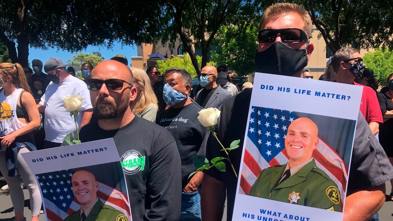 Dos residentes de Santa Cruz participan en una ceremonia en honor del sargento Damon Gutzwiller, quien falleció baleado en una emboscada.