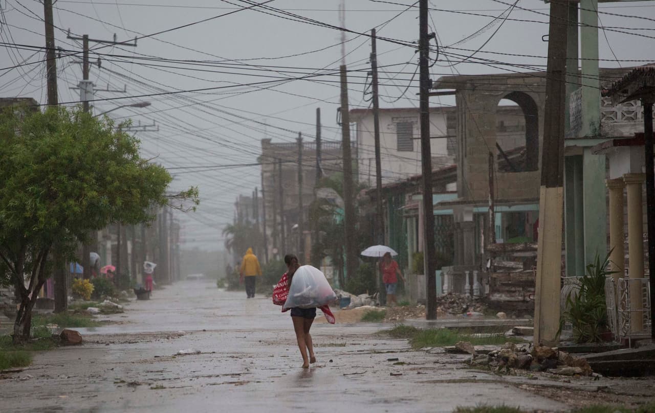 Residentes caminan bajo la lluvia en Caibarien, Cuba.