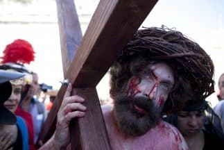 Un hombre interpretando a Jesucristo recorre las calles de Jerulaén con una Cruz el Viernes Santo.