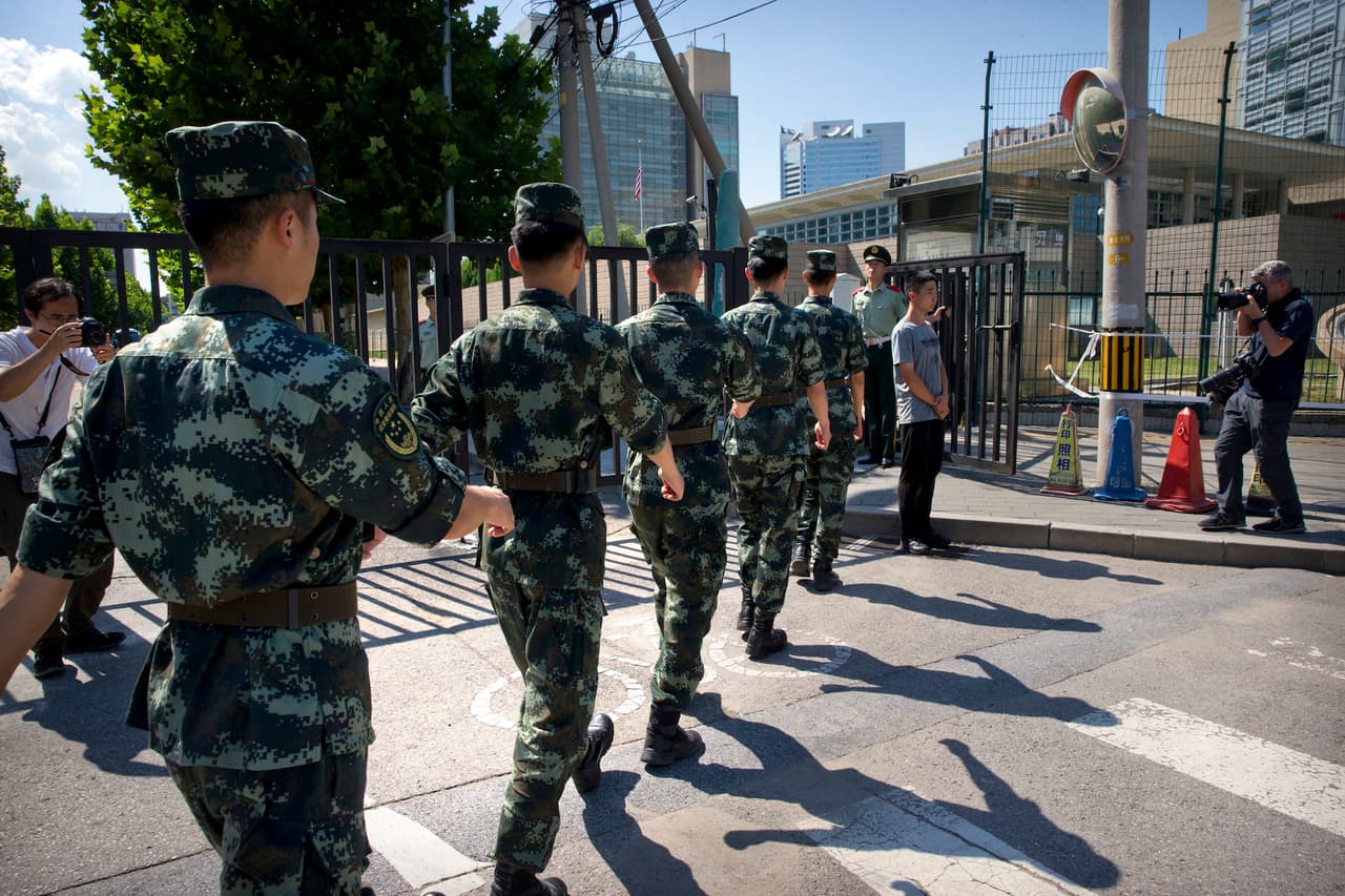 Chinese paramilitary police march in formation toward the U.S. Embassy in Beijing, in background, near the site of an incident, Thursday, July 26, 2018. A man exploded a small homemade bomb outside the U.S. Embassy in Beijing on Thursday, injuring only himself, according to police and an embassy spokesperson. (AP Photo/Mark Schiefelbein)