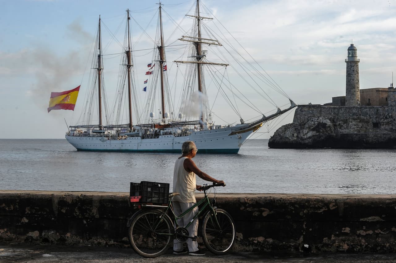 Un habitante de La Habana mira pasar al El buque escuela de la Armada española Juan Sebastián Elcano.