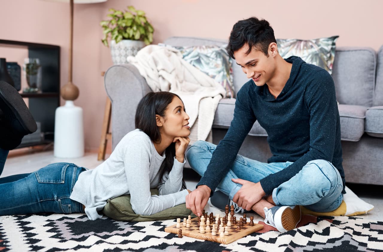 Its all fun and games in self quarantine. a young couple playing a game of chess at home.