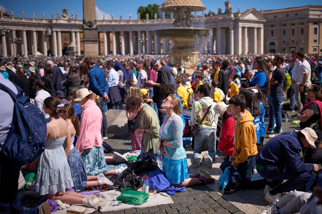 Creyentes rezando durante el funeral del papa Francisco en una plaza de San Pedro abarrotada de feligreses.
