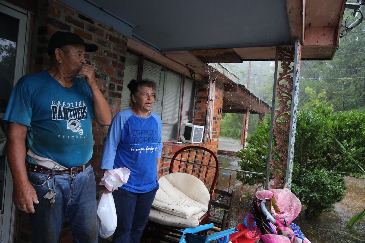 Una pareja espera por la ayuda de los miembros de la Armada Cajún, quienes se acercan a su hogar inundado en Lumberton.