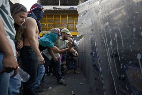 Los estudiantes desarmados confrontan verbalmente a la policía. Los estudiantes llevaron a cabo una manifestación pacífica contra el régimen del mandatario Nicolás Maduro el 12 de febrero de 2014. Motorizados uniformados y con sus caras cubiertas, dispararon contra los manifestantes, matando a dos estudiantes y a un oficial.